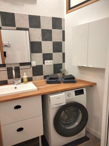 une salle de bain avec une machine à laver et un lavabo dans l'établissement Appartement 1er étage MÈZE, à Mèze