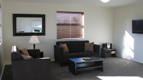 a living room with two couches and a table at Pegasus Gateway Motels & Apartments in Rangiora