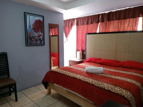a bedroom with a large bed with red sheets and a window at Hotel Puerto México Aeropuerto in Mexico City