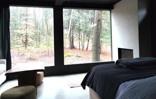 a bedroom with a bed and a large window at Black Pine Tree House in Acton