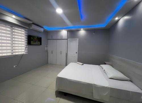Un dormitorio con una cama con una luz azul. en Hotel KP en Portoviejo