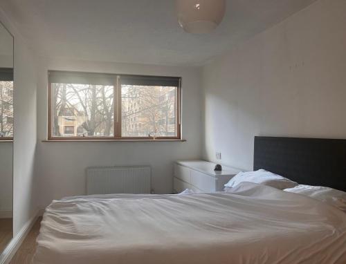 a white bedroom with a bed and a window at Charming Central London Apartment with Balcony in London