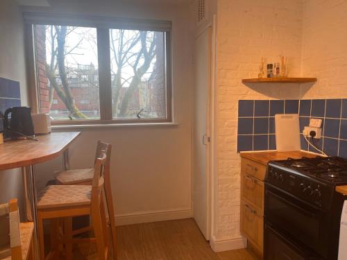 una cucina con piano cottura, tavolo e finestra di Charming Central London Apartment with Balcony a Londra