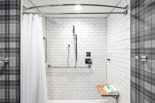 y baño con ducha de azulejos blancos. en Gravity Haus Steamboat, en Steamboat Springs