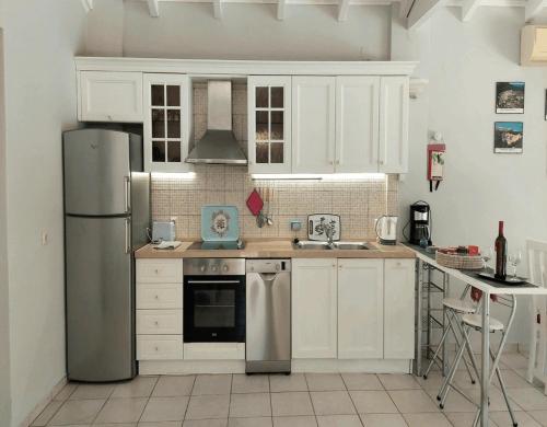 a kitchen with white cabinets and a stainless steel refrigerator at Villa Persephone in Halikounas