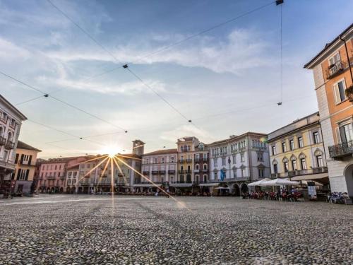 a city street with buildings and the sun in the sky at Loft DV1 - Bellissimo loft in Città Vecchia Locarno in Locarno