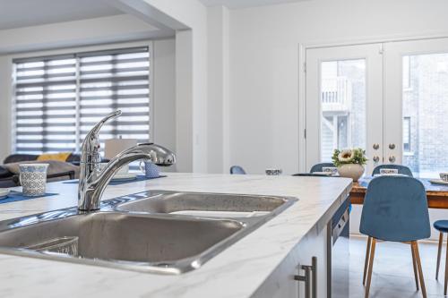 una cocina con fregadero de acero inoxidable y sillas azules en Spacious 5-Bedroom Home with 4.5 Bathrooms: 3 Sassafras Road, en Midhurst