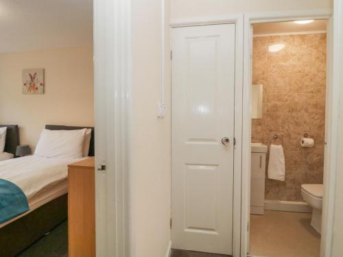 a bedroom with a bed and a bathroom with a toilet at Wren's Nest Manorcombe in Callington
