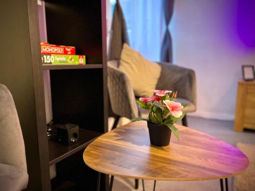 a wooden table with a vase with flowers on it at G&G Luxury Apartment am Stadtpark Bendorf in Bendorf