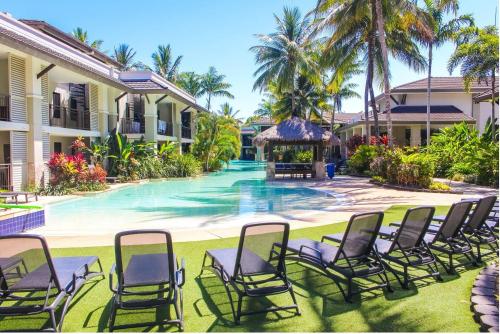 a group of chairs sitting around a swimming pool at The Posh Penthouse With Stunning Rooftop Oasis, Free Parking And WIFI in Port Douglas