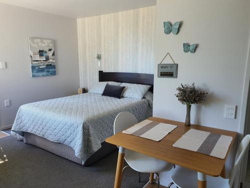 1 dormitorio con cama, mesa y mariposas en la pared en MoanaViews, en Nelson