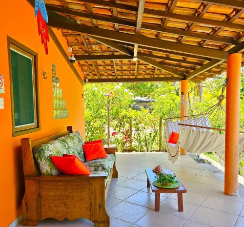 a porch with a couch and a hammock and a table at Villa Mar a Vista - Suite Alamanda in Cumuruxatiba