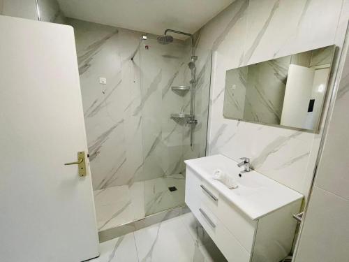 y baño blanco con lavabo y ducha. en Appart Neuilly bagatelle Porte Maillot 4 Pers en Neuilly-sur-Seine