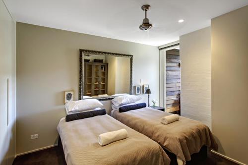 two beds in a room with a mirror at Byron Butter Factory Apartments in Byron Bay