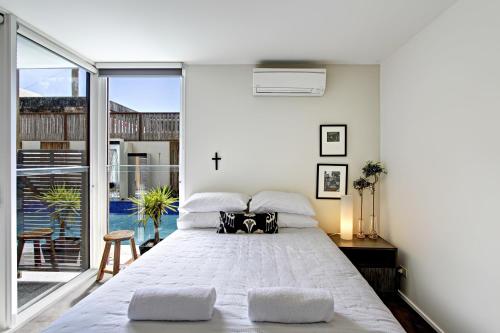 a bedroom with a large bed and a large window at Byron Butter Factory Apartments in Byron Bay