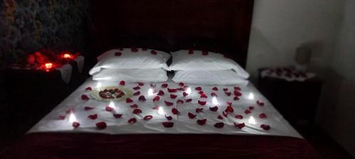 a bed with red roses on it with candles on it at Ferrara Rooms in Paços de Ferreira