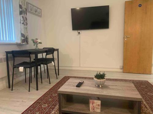 ein Wohnzimmer mit einem Tisch und einem TV an der Wand in der Unterkunft Cozy flat in Birmingham with Parking in Birmingham