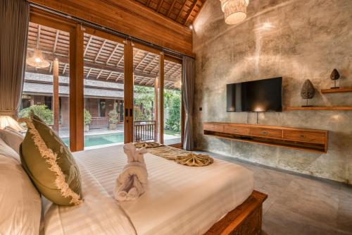 a bedroom with a bed with a tv on the wall at Villa Walet in Tumbak Bayuh