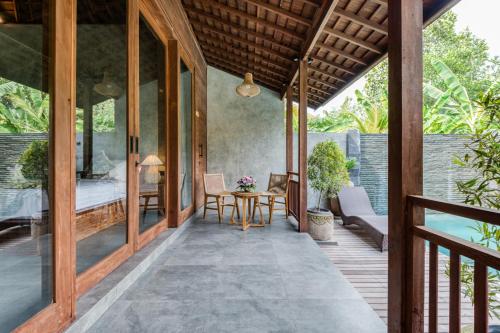 a room with a bed and a table on a deck at Villa Walet in Tumbak Bayuh