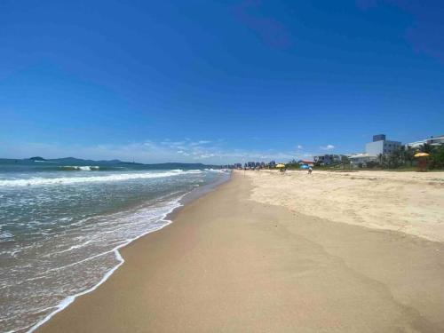 a sandy beach with the ocean on a clear day at Casa de praia aconchegante in Barra Velha