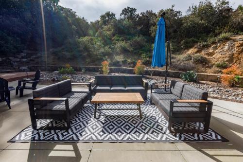 a patio with couches and a table and a blue umbrella at Elite Retreat! Hot Tub, Arcade, & Theater. 6 Beds! in Encinitas