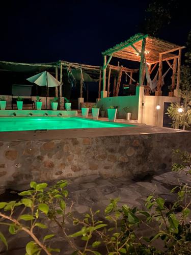 a swimming pool at night with chairs and umbrellas at Tierra Madre Hotel Boutique in Comonfort