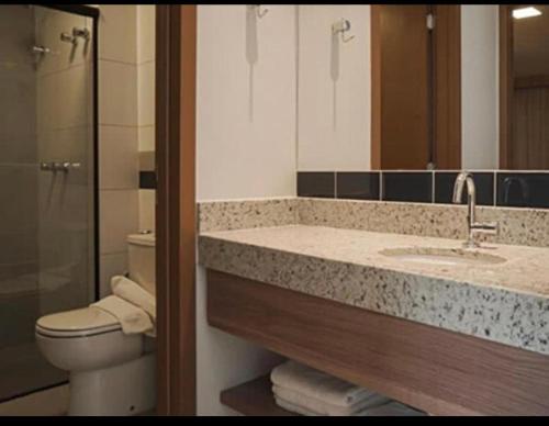 ein Badezimmer mit einem Waschbecken, einem WC und einem Spiegel in der Unterkunft Praias do Lago Ecoresort in Caldas Novas
