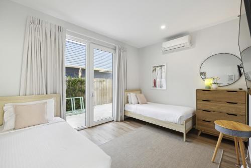 a white bedroom with two beds and a window at Tea Trees in Woolgoolga