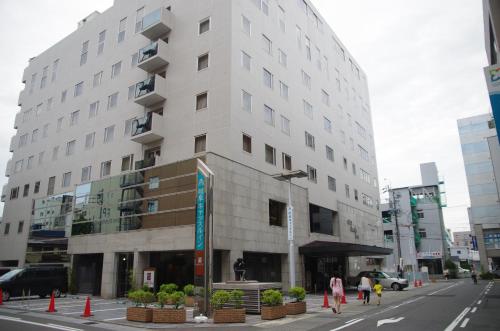 a white building on a city street with people walking past it at Gifu Castle Inn in Gifu