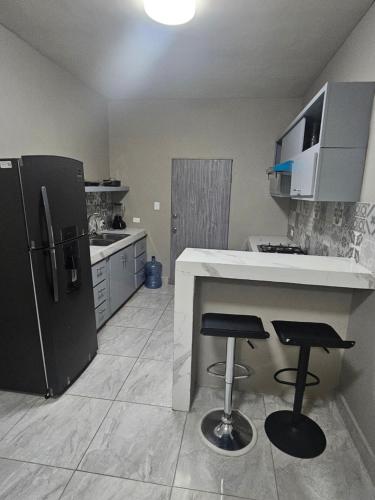 eine Küche mit einem Kühlschrank und 2 Barhockern in der Unterkunft Departamento madroño in Heroica Matamoros