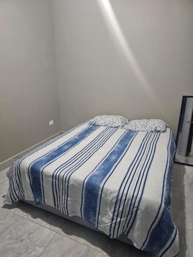 a bed with a blue and white striped comforter in a room at Departamento madroño in Matamoros