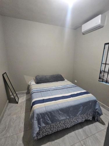 Un dormitorio con una cama con una manta azul. en Departamento madroño, en Matamoros