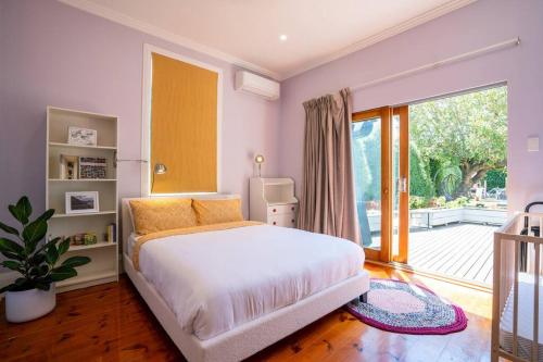 a bedroom with a white bed and a large window at Entire holiday house - Geelong - Sleeps 6 in Belmont