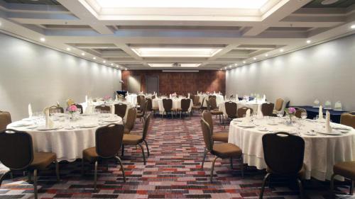 a room filled with tables and chairs with white tablecloths at InterContinental Santiago by IHG in Santiago