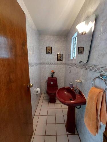 een badkamer met een rode wastafel en een toilet bij Casa Chapultepec-Morelia in Morelia