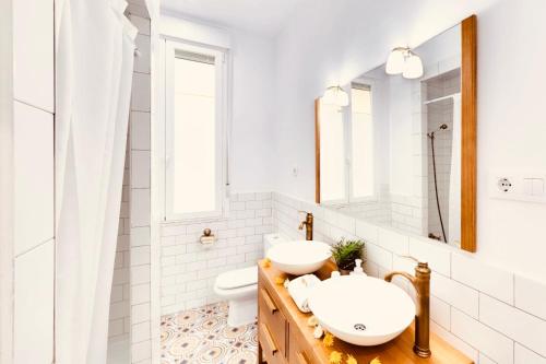 Baño blanco con 2 lavabos y espejo en Hostal Patria Madrid, en Madrid