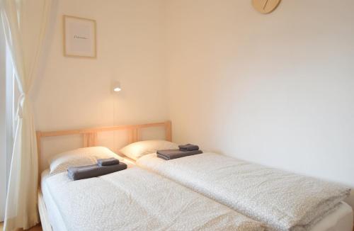 two beds in a small room with white sheets at Peaceful Studio Apartment near Center in Innsbruck