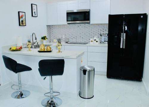 a kitchen with a black refrigerator and two bar stools at Luxury Studio only 5 miles to IAH in Humble