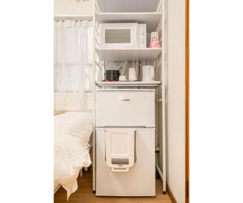 a white refrigerator in a room with a microwave on a shelf at 秋 5GWIFI*東京千代田区皇居1km~King BLdg. in Tokyo