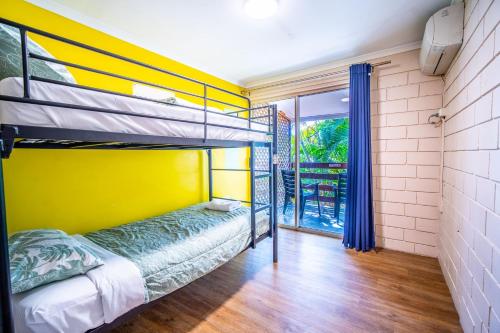 a bedroom with bunk beds and a yellow wall at The Hostel, Airlie Beach in Airlie Beach