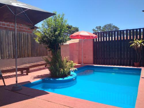 uma pequena piscina com um guarda-sol em Cabañas El Hornero em Puerto Iguazú