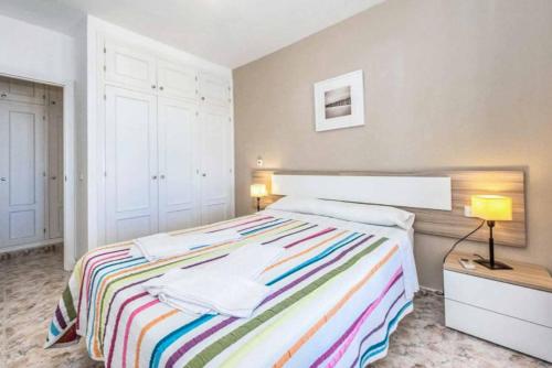 um quarto com uma cama com um cobertor listrado colorido em Bellavista Mar em Arenal d'en Castell