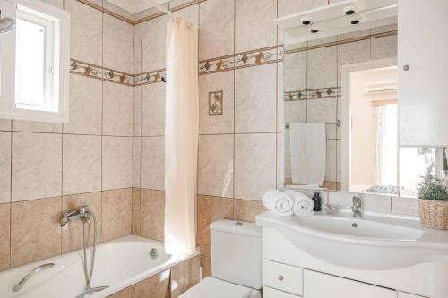 a bathroom with a tub and a sink and a toilet at Villa Angeliki Skala in Spathíon