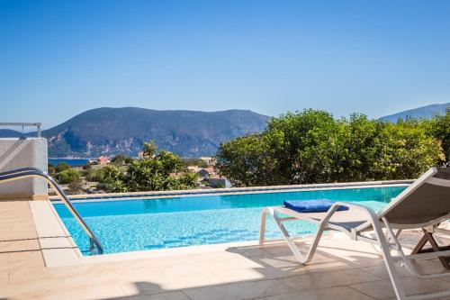a swimming pool with a chair and a table and a chair at Evanthia by Vintage Travel in Fiskardho