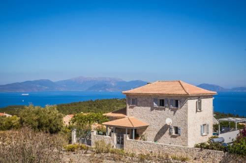 a stone house on a hill with the ocean in the background at Evanthia by Vintage Travel in Fiskardho