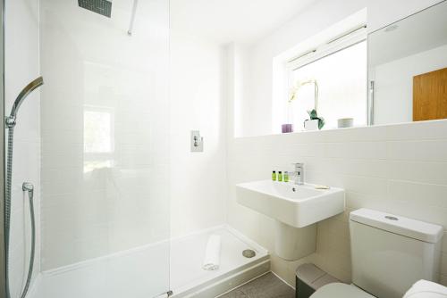 une salle de bain blanche avec un lavabo et une douche dans l'établissement Luxury property with spa access on a nature reserve Damselfly HM105, à Somerford Keynes