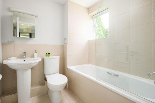 La salle de bains est pourvue de toilettes, d'un lavabo et d'une baignoire. dans l'établissement Lakeside property with spa access on a nature reserve Keel House CW23, à Somerford Keynes