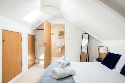 a white bedroom with a large bed and a bathroom at Lakeside property with spa access on a nature reserve Kingfisher Lodge CW80 in Somerford Keynes