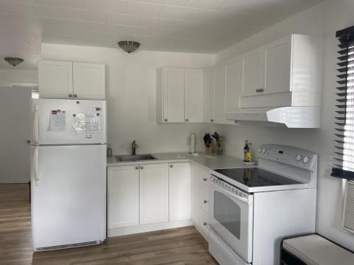 a white kitchen with white appliances and white cabinets at 4 Pièces, stationnement et tennis in Saguenay