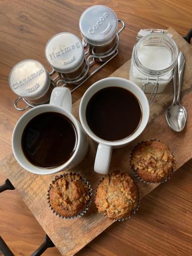 zwei Tassen Kaffee und Muffins auf einem Holztisch in der Unterkunft Elesel Lodge 